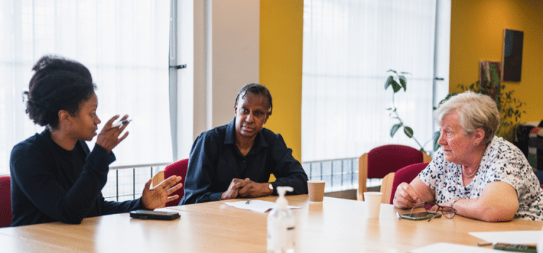 Three people sitting around a table having a conversation.